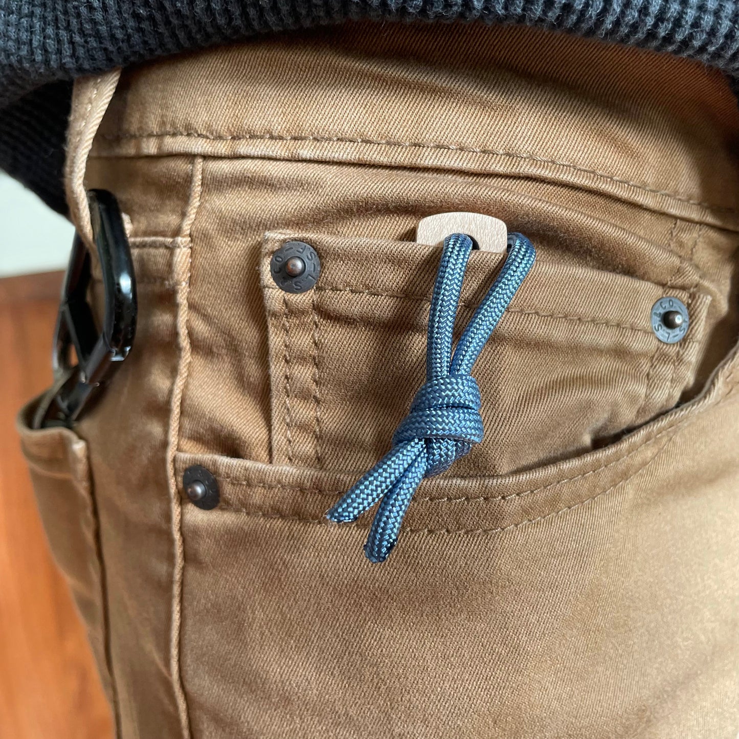 Thumbhill shown in small coin pocket of jeans with lanyard hanging out for grabbing onto.