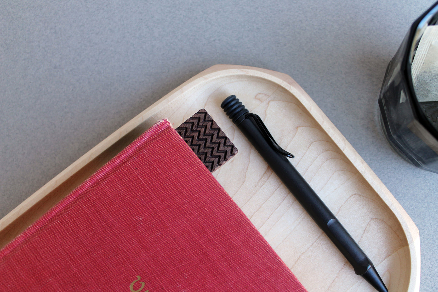 Detail view of Zigzag bookmark in red book on a tray with pen and tea glass beside it.