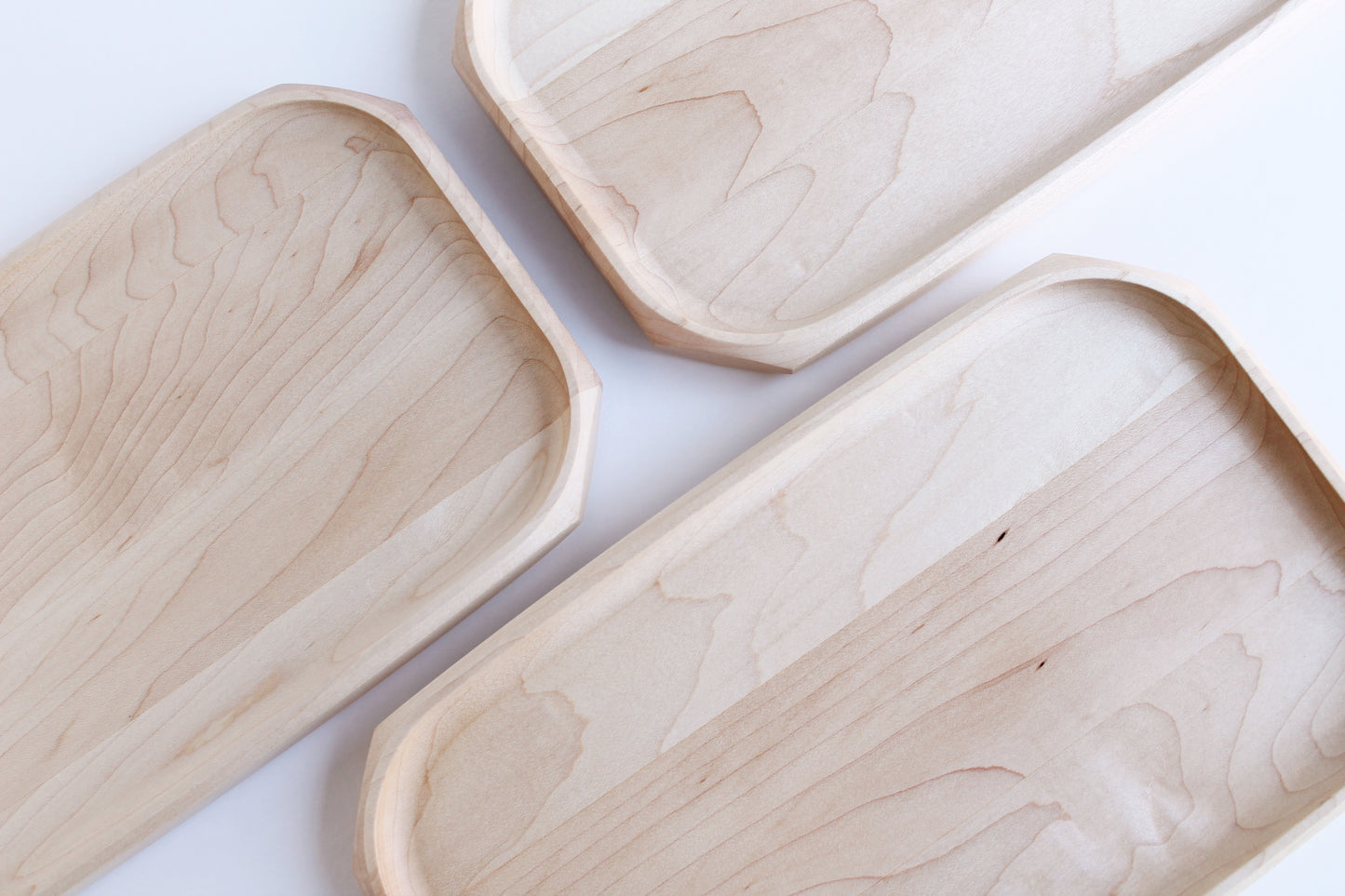 Three Genesis Tray in Maple wood on white background. Top view showing various maple wood grains on different trays.