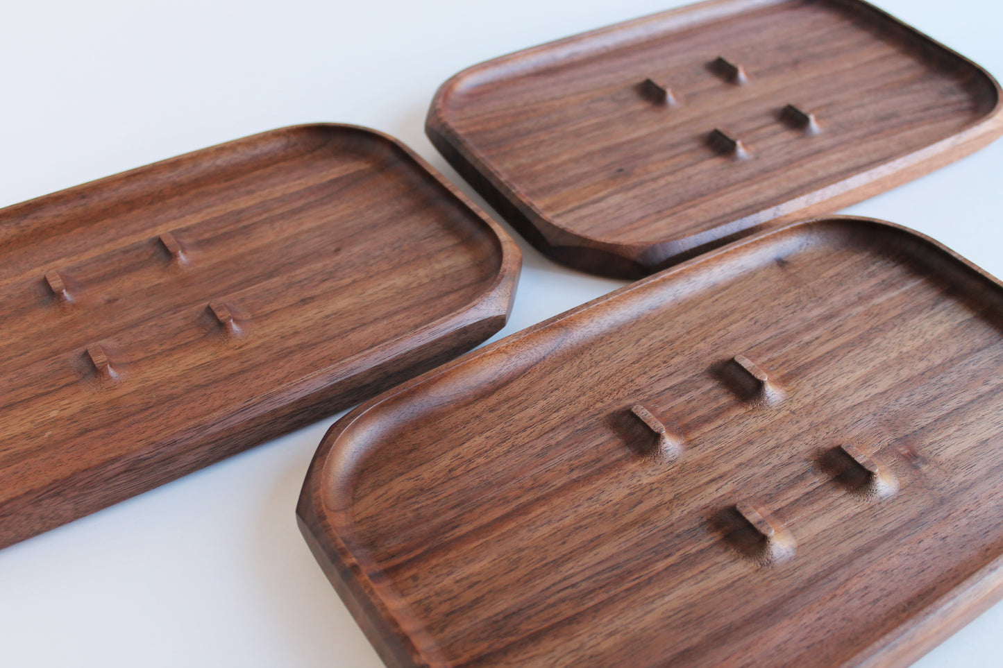 EDC Park Tray in Walnut tray with center ramps for everyday carry items. View of 3 trays showing various grains of walnut wood.