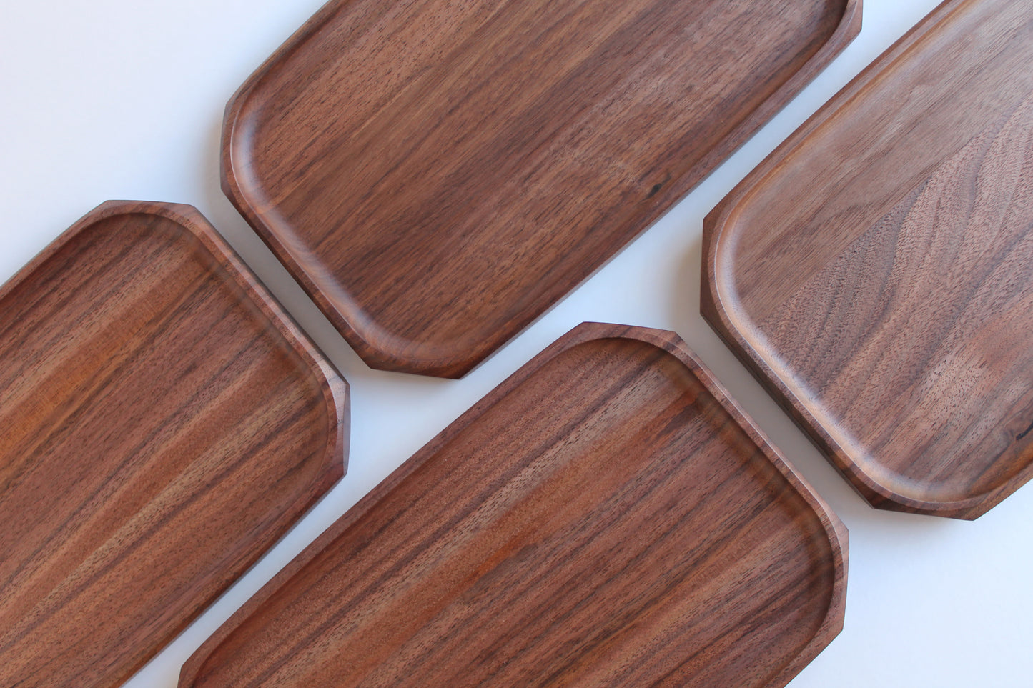 Genesis Tray in Walnut wood on white background. Top view showing four trays with various walnut wood grains.