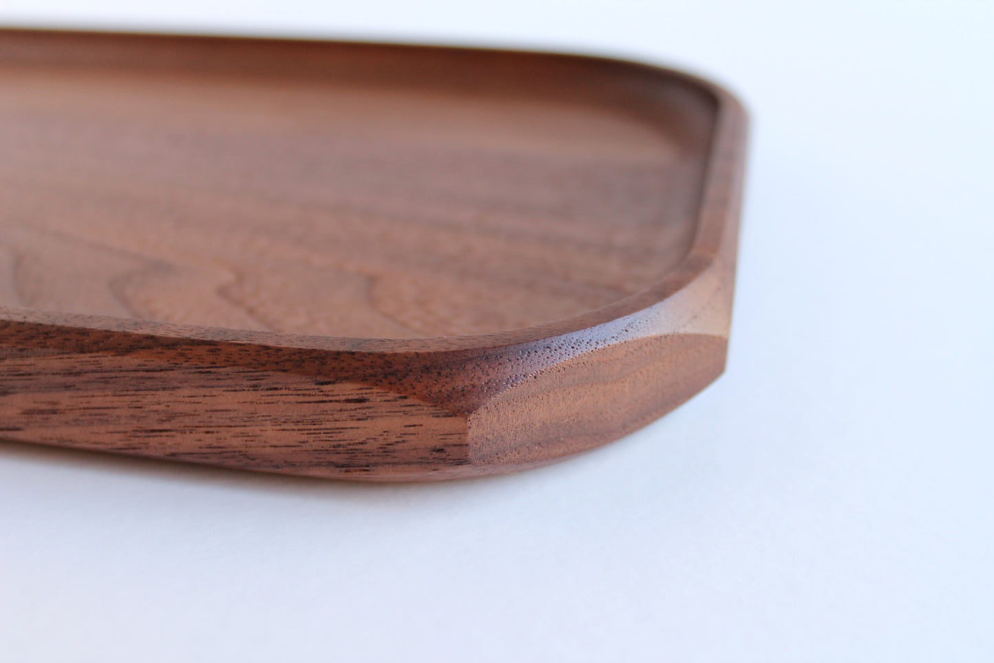 Genesis Tray in Walnut wood on white background. Corner detail view showing chamfer detail.