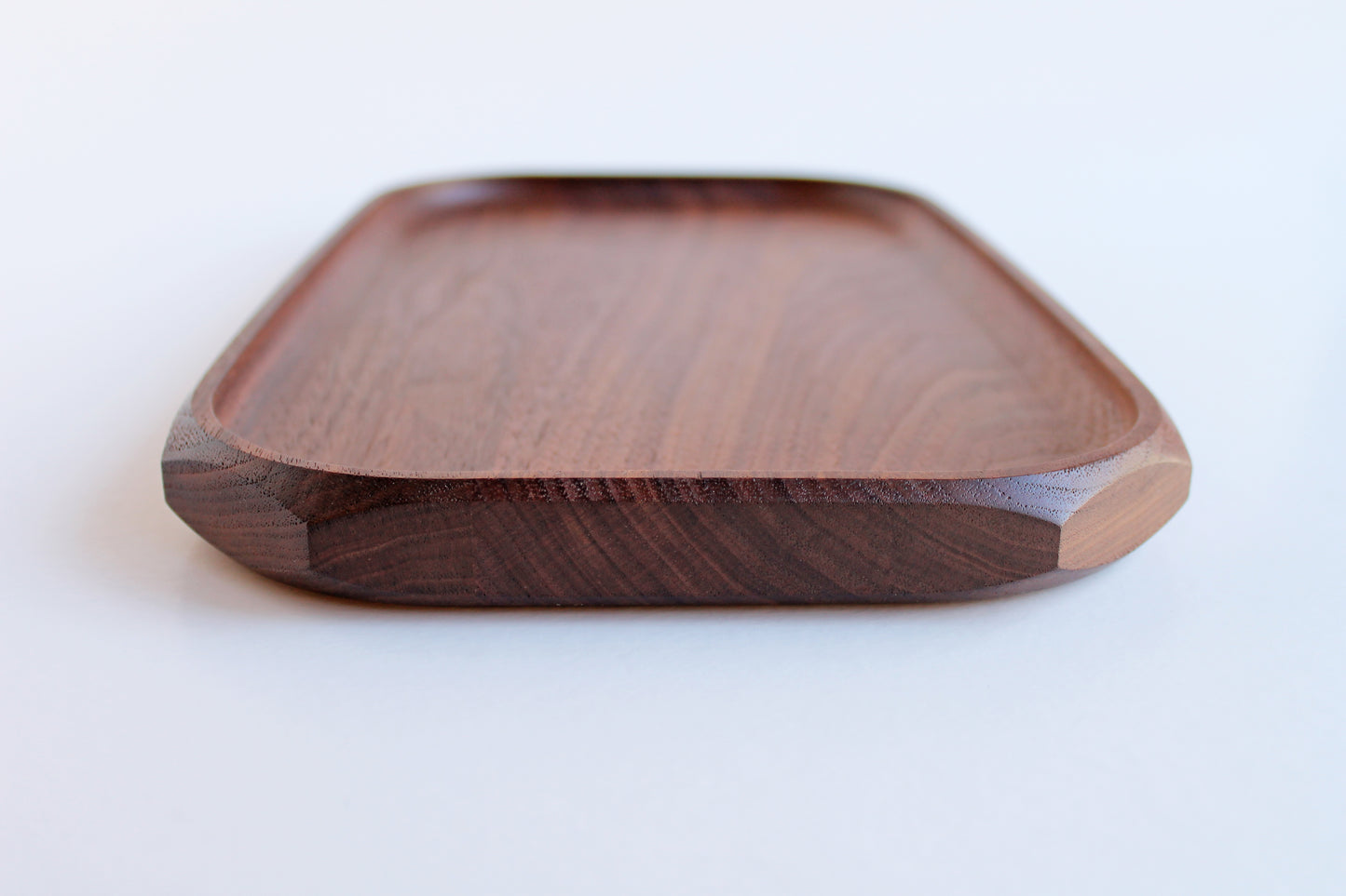 Genesis Tray in Walnut wood on white background. End view showing chamfer detail.