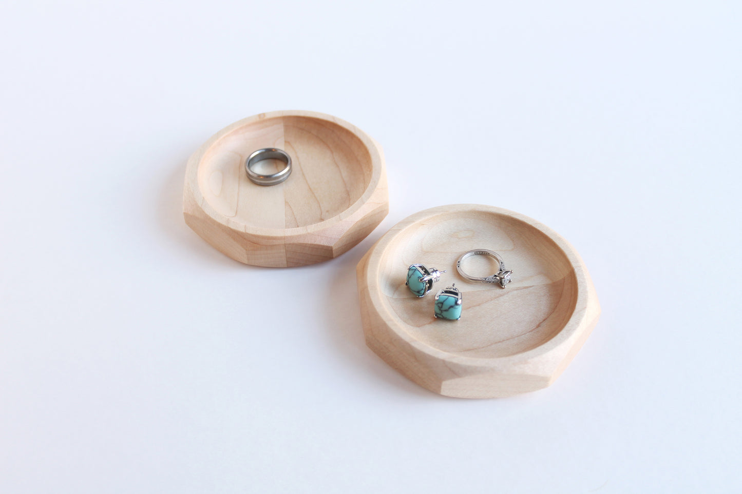 Two Genesis Dishes in maple on white background with rings and earrings in them.