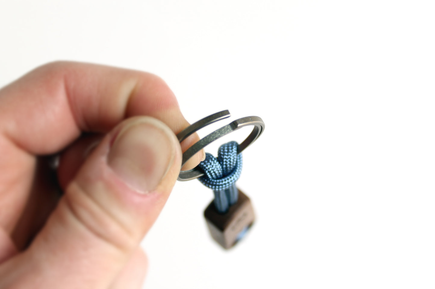 Core Key Fob with Titanium Key Ring, Paracord Lanyard and Maple Fob. Detailed view of thumb pushing titanium key ring to side.