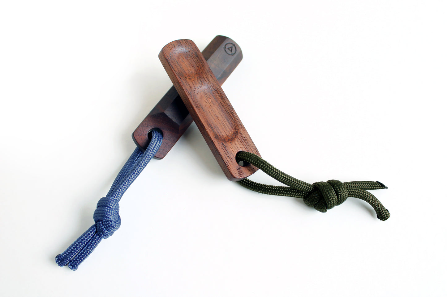 Two Thumbhill's shown in walnut with one facing up and other showing bottom. Lanyards are olive and steel blue lanyard. Alternate angled view.