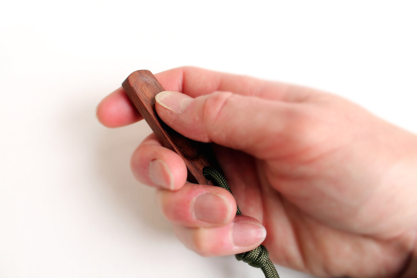 Thumbhill in Walnut held in persons hand with lanyard at bottom. Thumb show rubbing across thumbhill portion of slide surface.