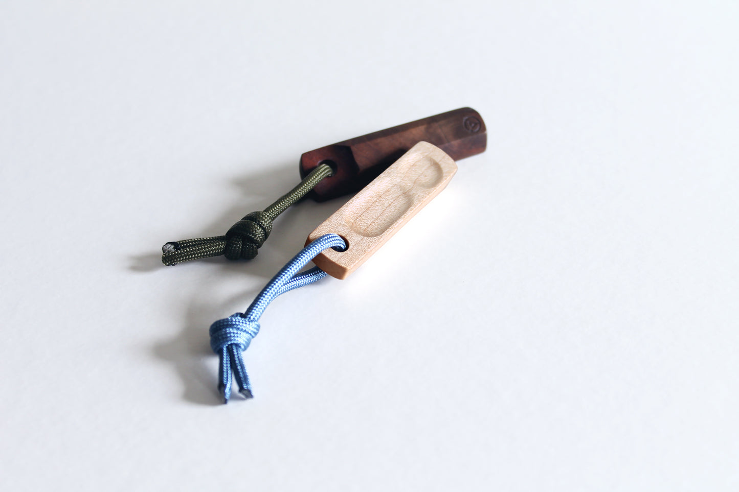 Thumbhill detailed view of maple version top side with steel blue lanyard and walnut version bottom side with olive lanyard.