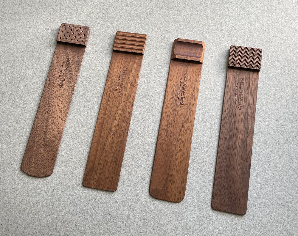 Four walnut Edge Bookmarks with the upper edge step shown different engraved textures on a gray background. Perforated, Flutes, Groove and Zigzag. Alternate angled view.