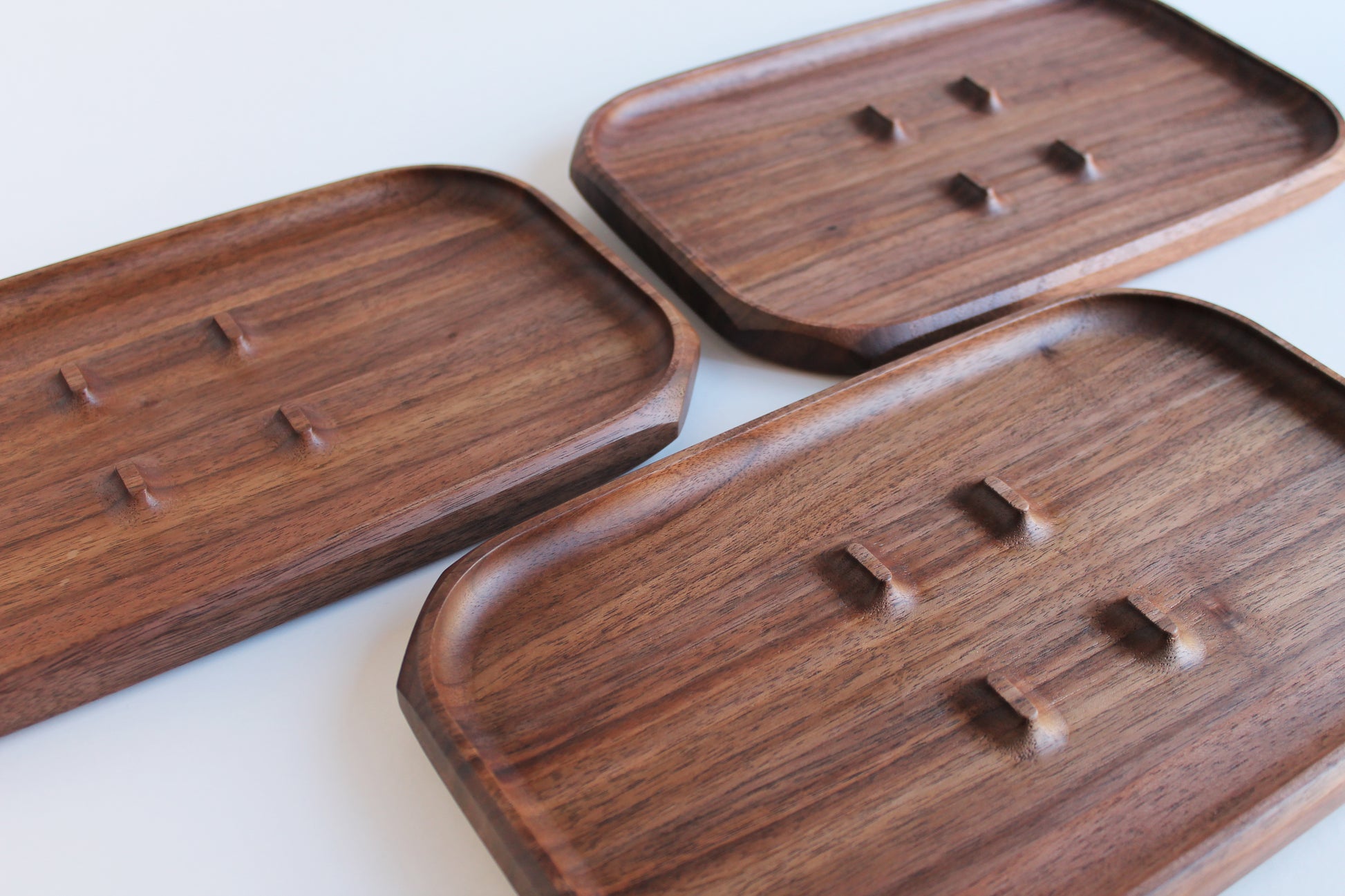 EDC Park Tray in Walnut tray with center ramps for everyday carry items. View of 3 trays showing various grains of walnut wood. 